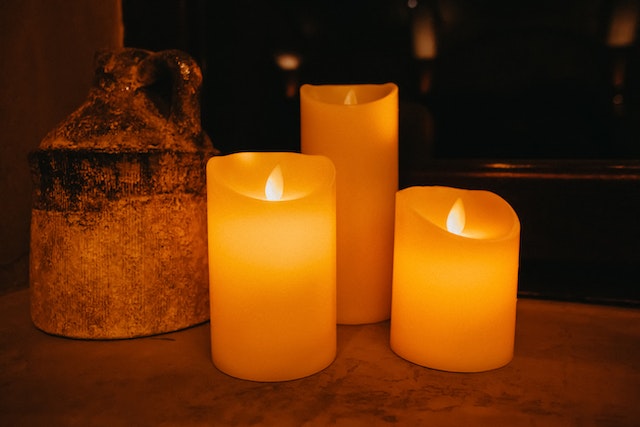 Three lit candles on a smooth surface
