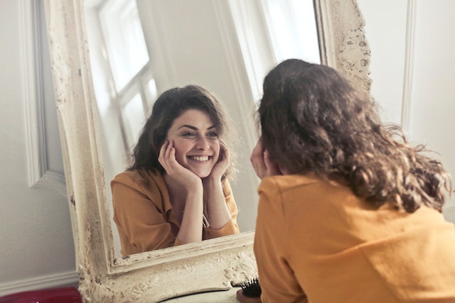 a smiling woman showing you ways to decorate your home with mirrors