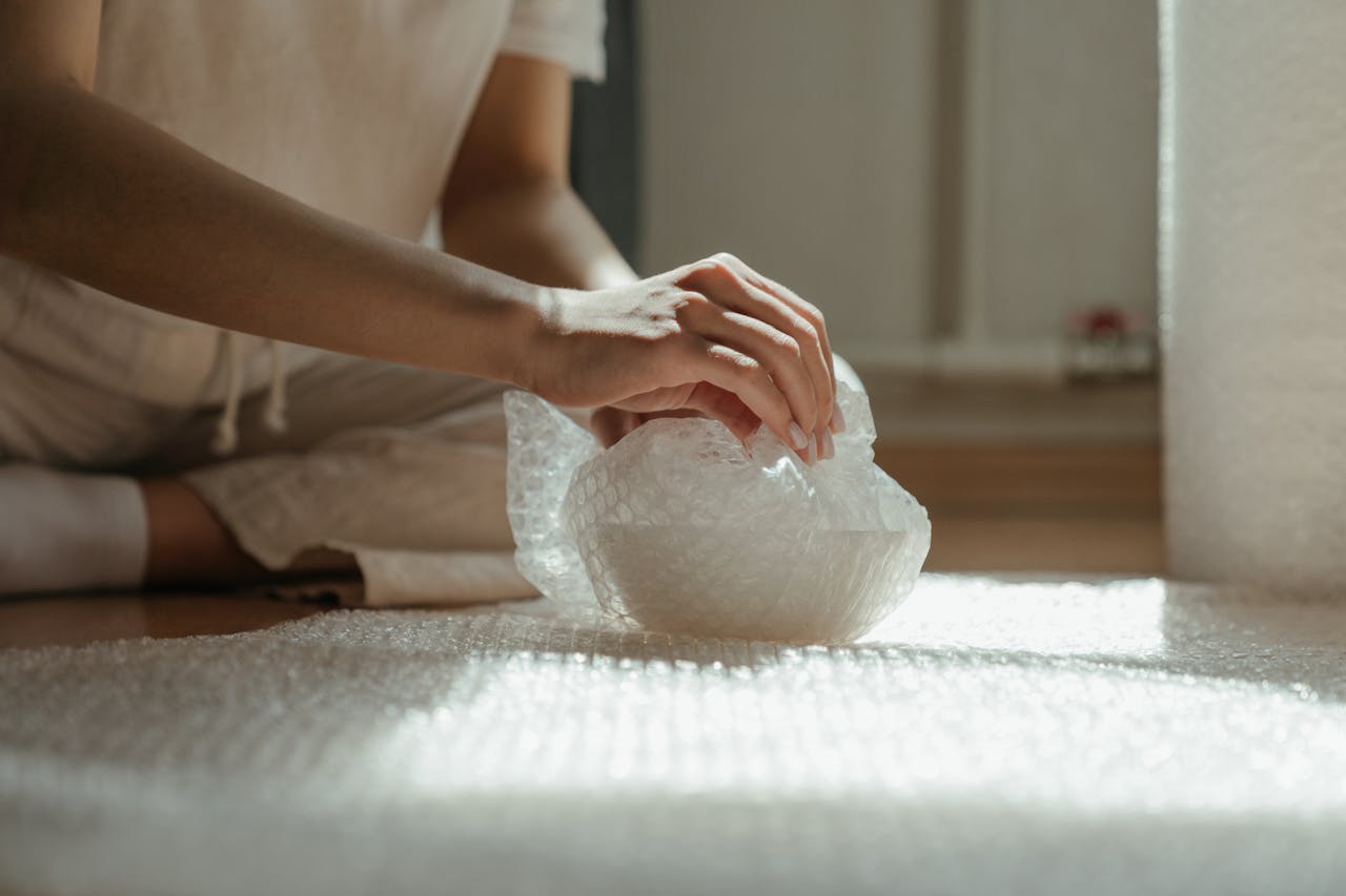 Person packing pottery in bubble wrap.