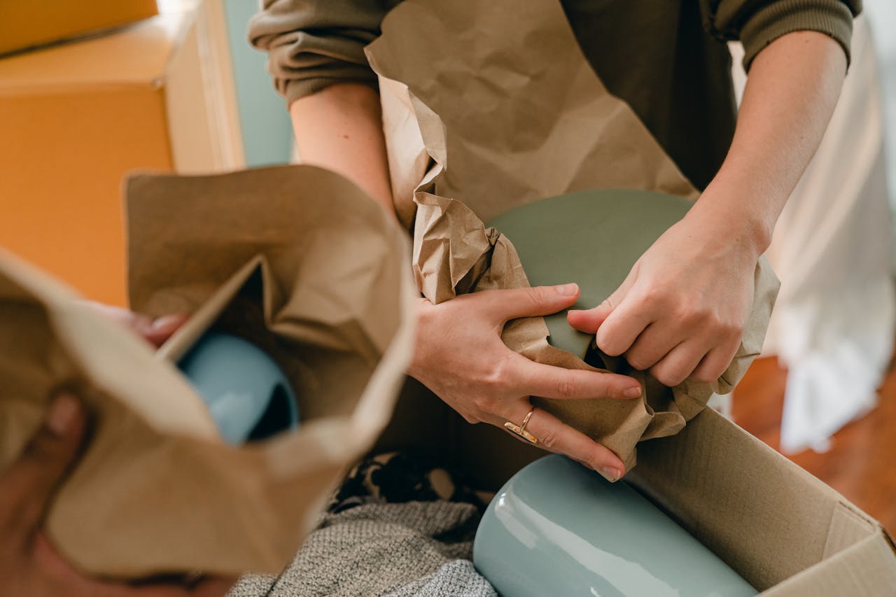 Two persons packing tableware in parchment.