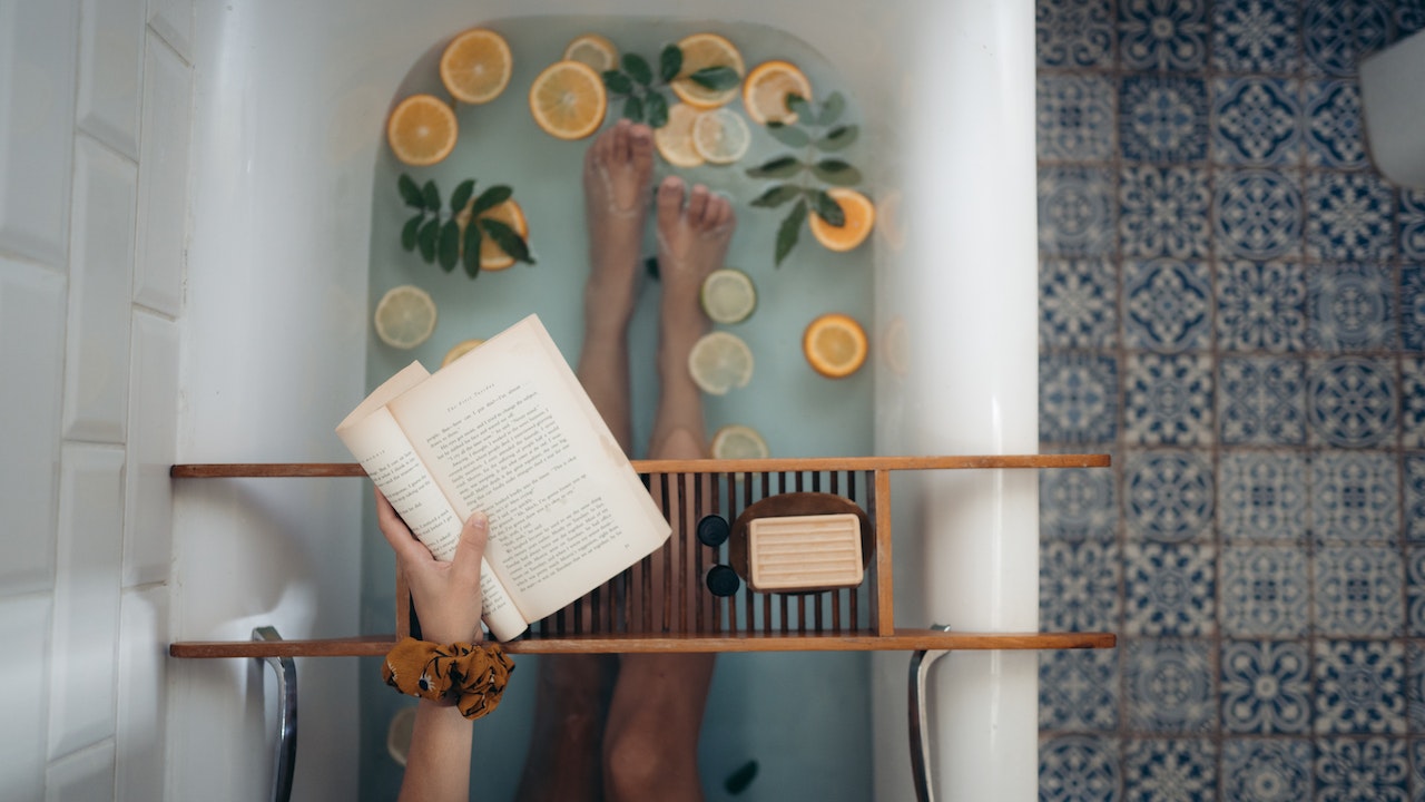 A woman reading a book while taking a relaxing bath.