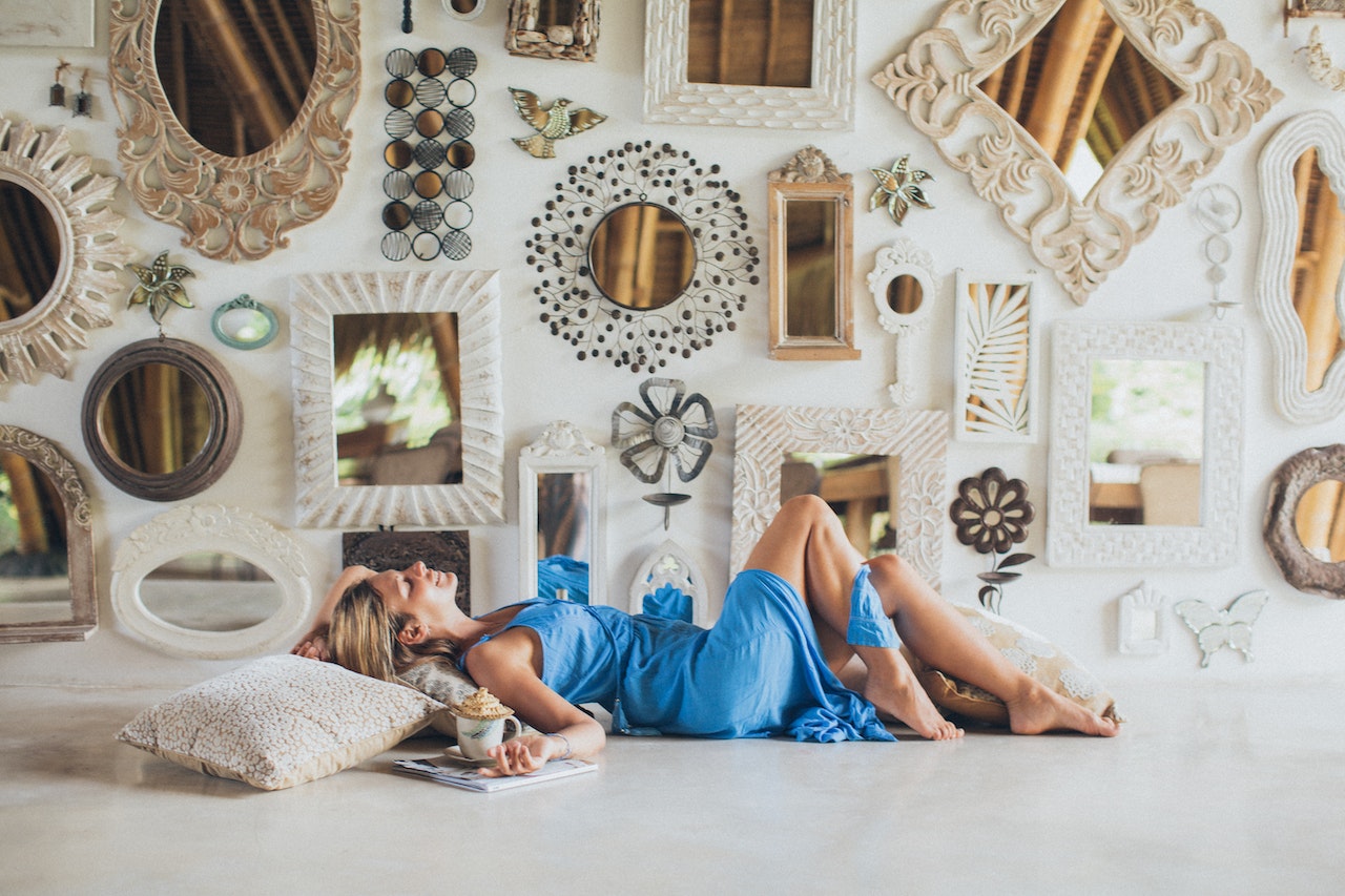 A woman next to a wall with many vintage mirrors.