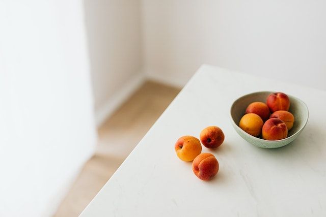 A bowl of peaches on a table.