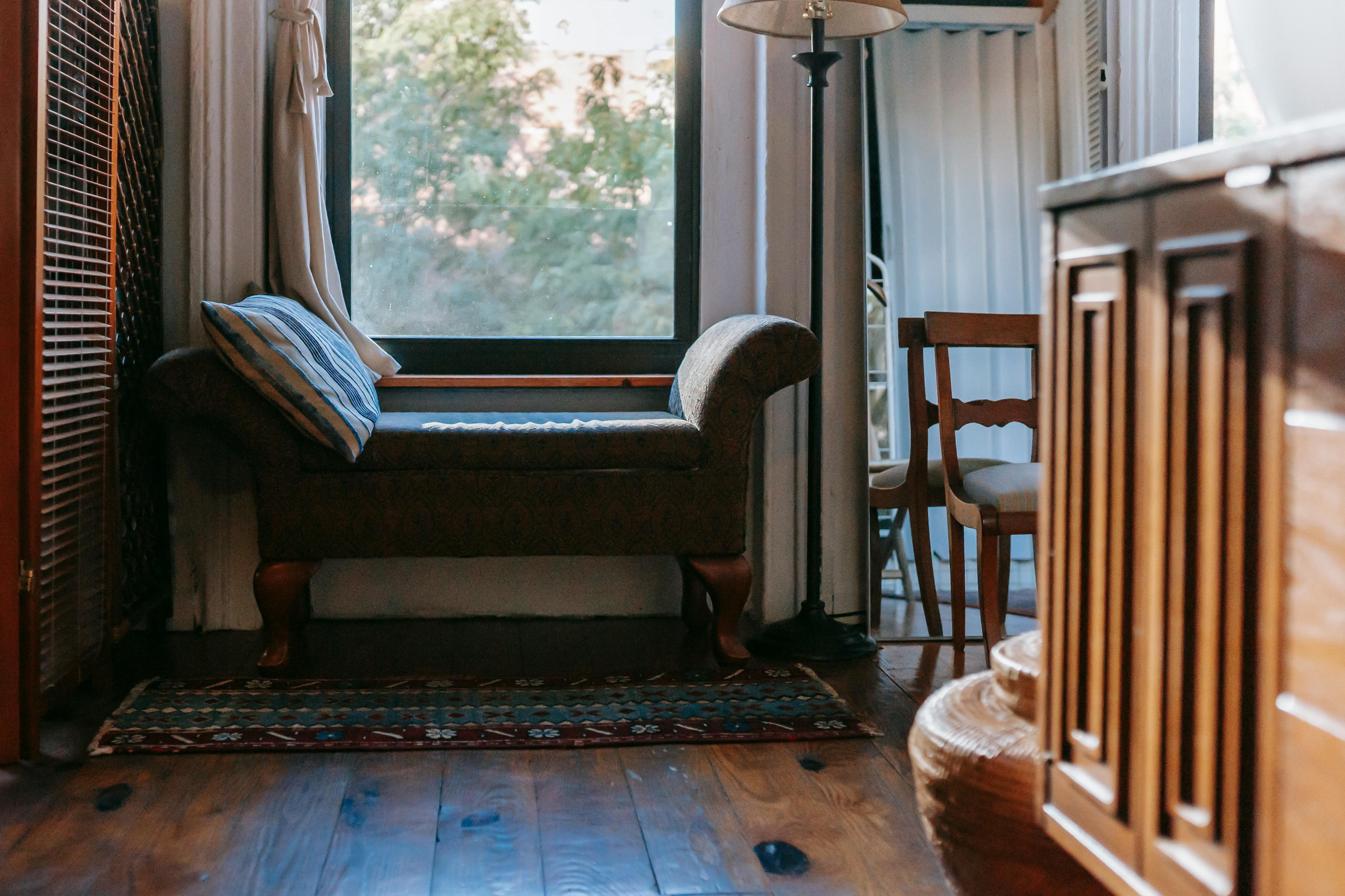 Ottoman chair with throw pillow near a window