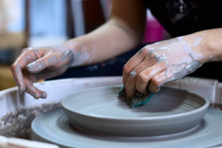 Closeup of a woman making a grey clay plate