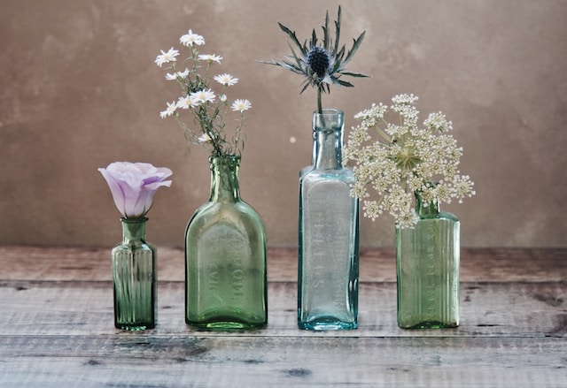 Different glass bottles with flowers in them to symbolize the versatility of glass pottery