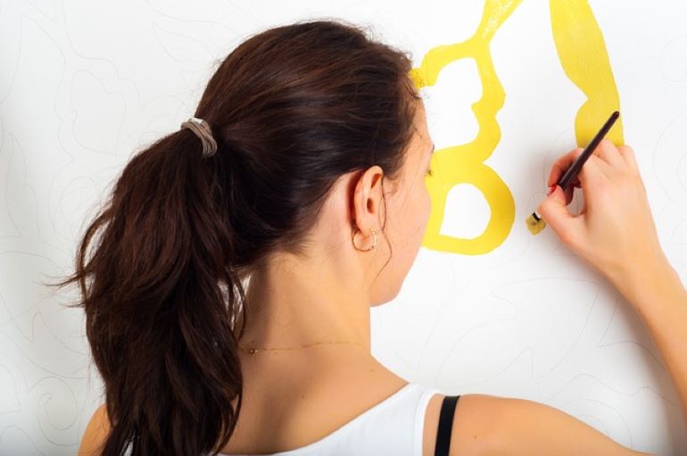  A woman is drawing on the wall.